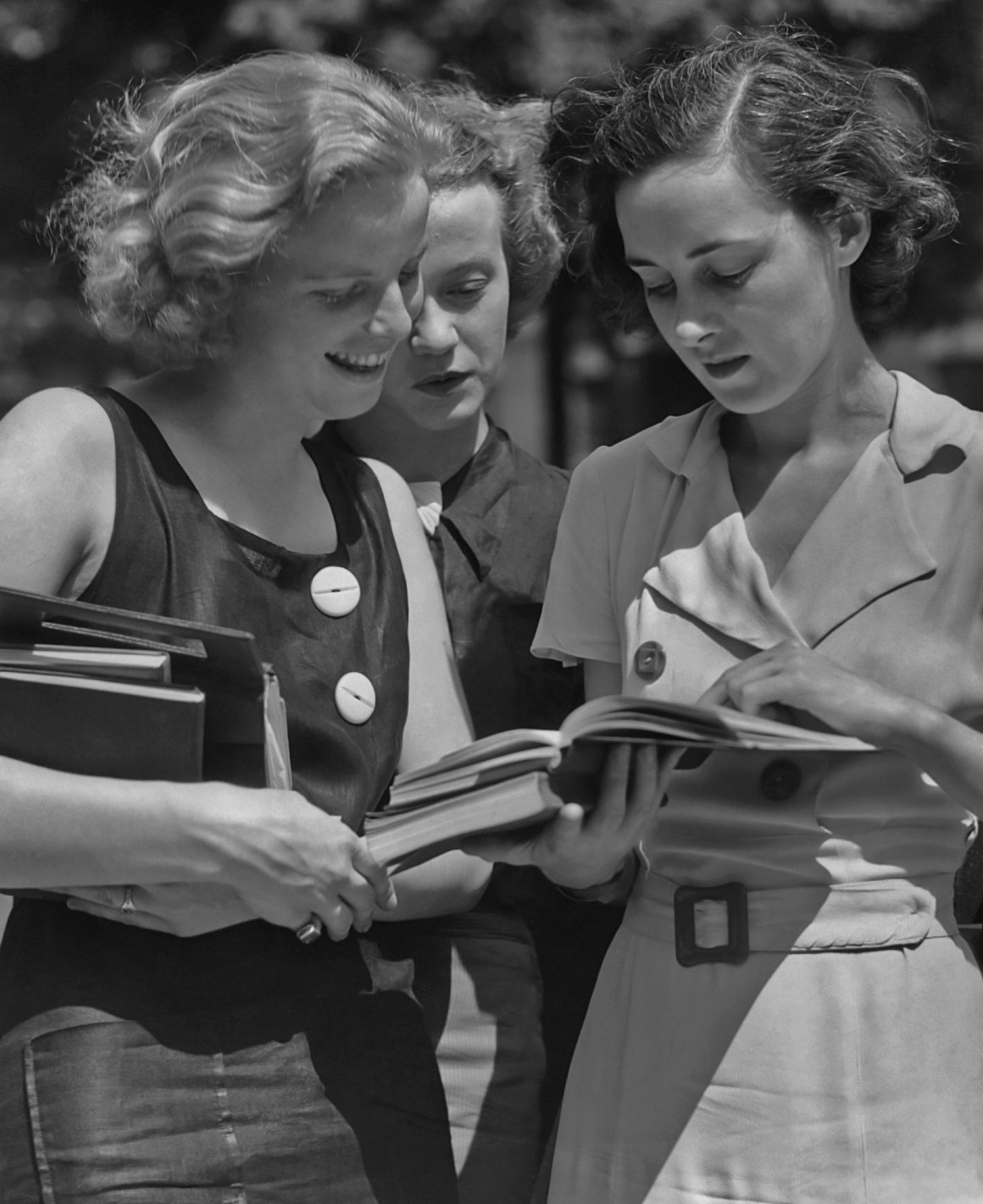 Three female students reading a book circa 1950.