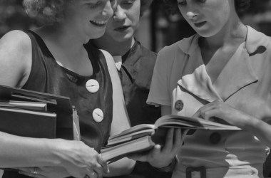 Three female students reading a book circa 1950.