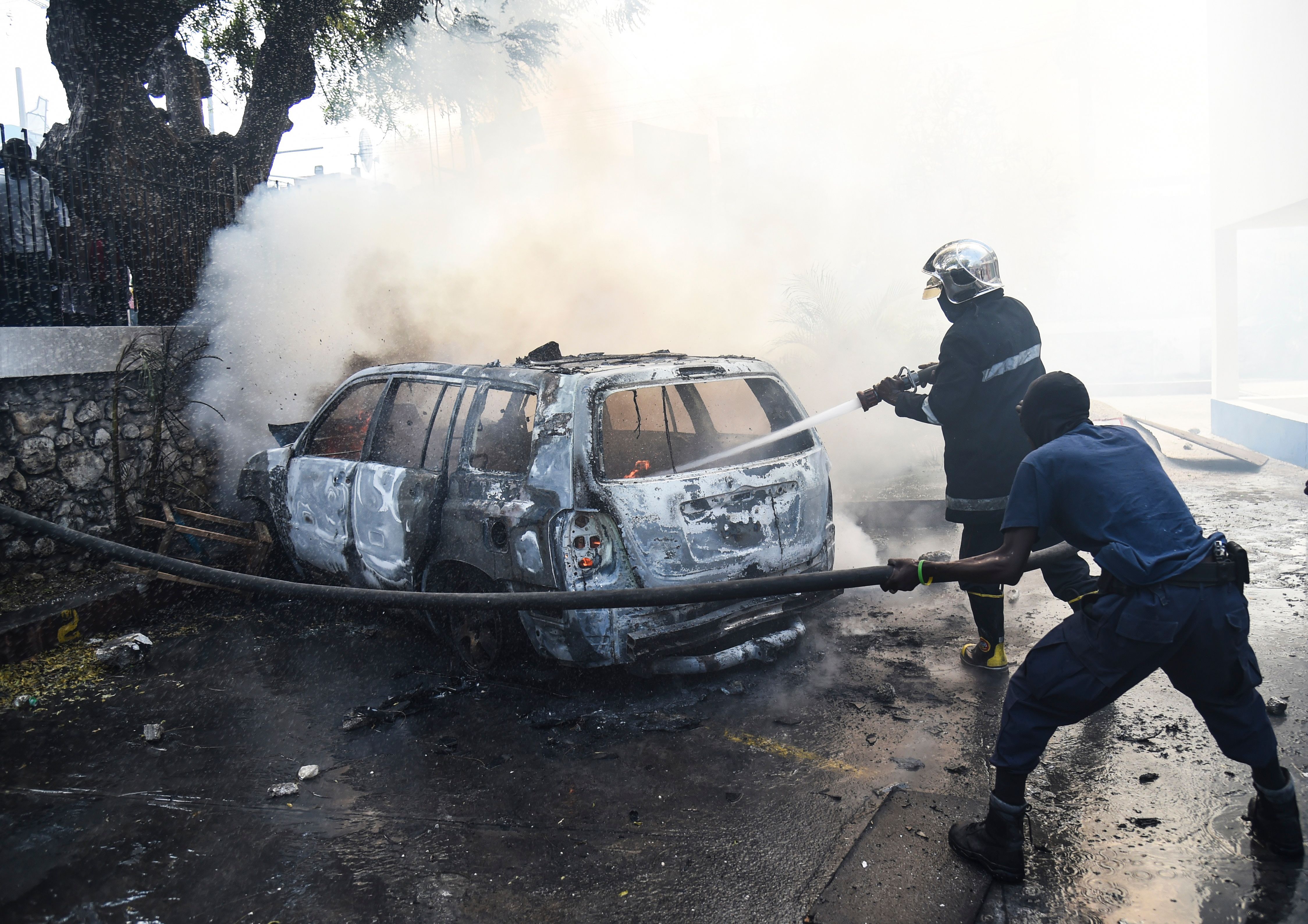 Firemen extinguish burning cars at the offices of Television Nationale d'Haiti in the Haitian capital of Port-au-Prince, on February 13th, 2019, the seventh day of protests against Haitian President Jovenel Moise and the misuse of the PetroCaribe fund.