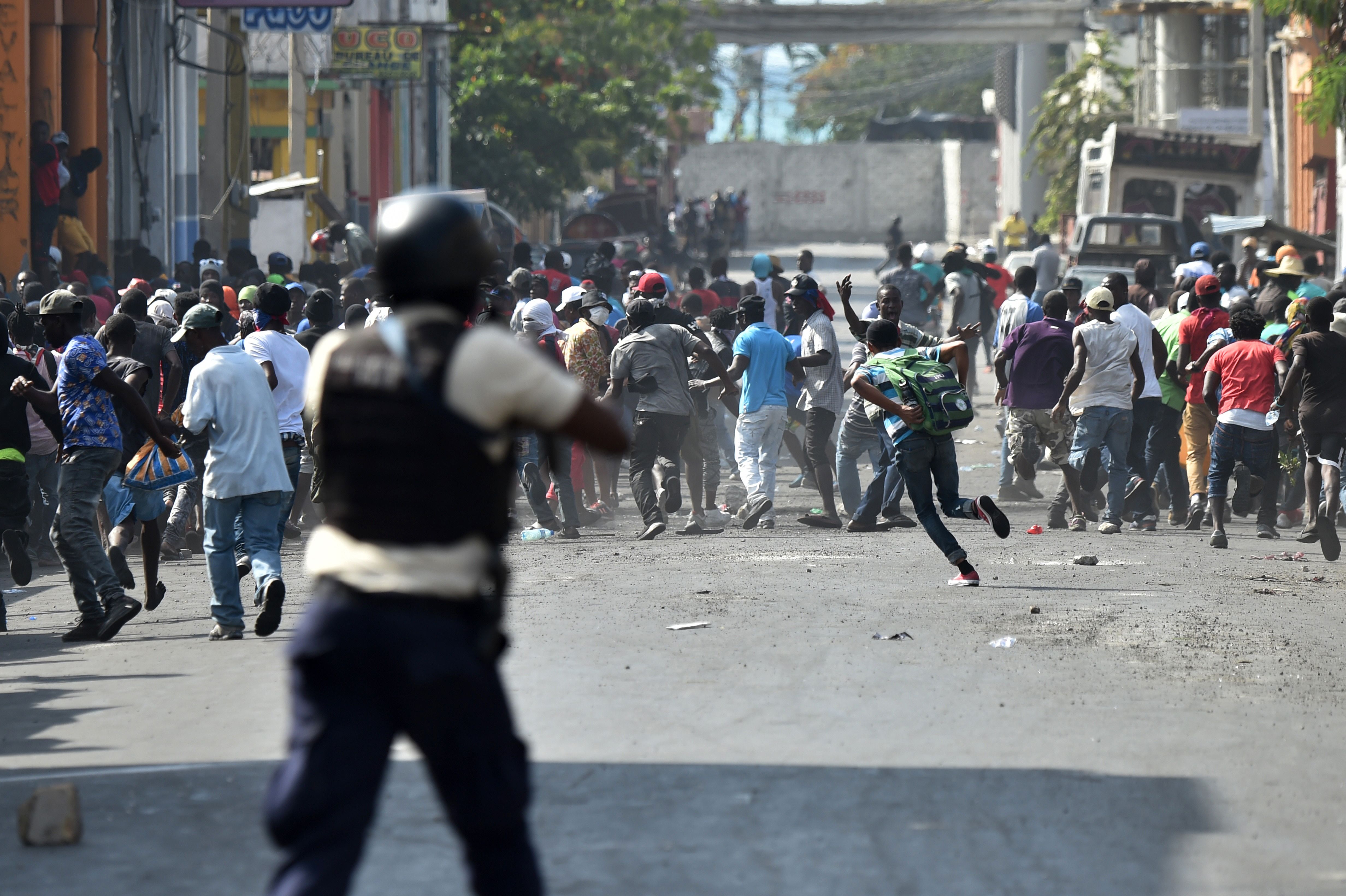 Demonstrators flee as Haitian police open fire during the clashes in the center of Port-au-Prince on February 13th, 2019, the seventh day of protests against Haitian President Jovenel Moise and the misuse of the PetroCaribe fund.