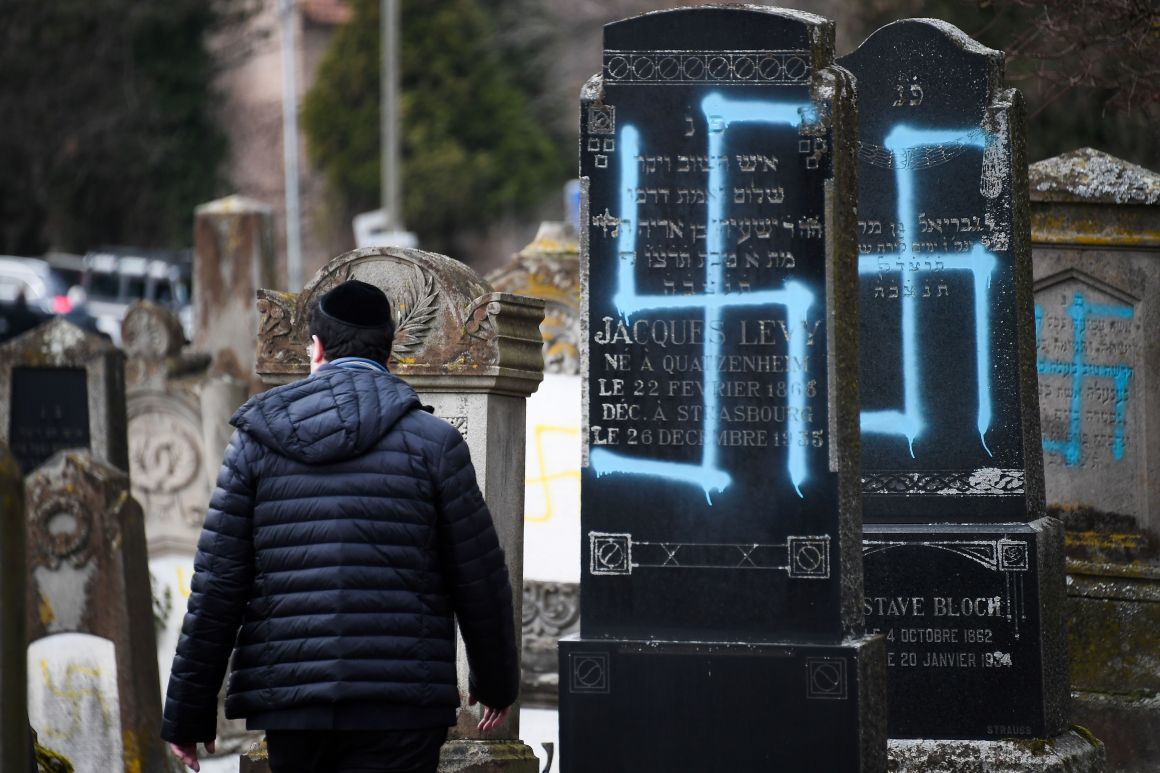 A man walks by graves vandalized with swastikas at the Jewish cemetery in Quatzenheim, France, on February 19th, 2019, the day of a nationwide march against a rise in anti-Semitic attacks. Around 80 graves have been vandalized at the Jewish cemetery in the village, close to the border with Germany in the Alsace region. The graffiti was discovered early Tuesday, according to a statement from the regional security office.