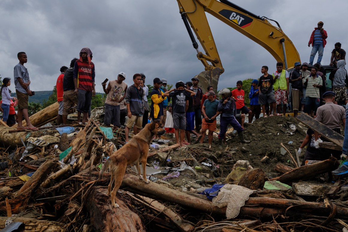 Indonesians watch as rescue workers dig through rubble looking for victims of the recent flash floods on March 19th, 2019, in Sentani, West Papua province, Indonesia. At least 89 people have died and nearly 7,000 have been displaced from their homes after three straight days of heavy rain led to massive flash flooding, which brought down massive trees and boulders from the surrounding mountains, crushing hundreds of homes.