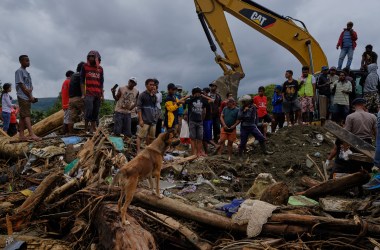 Indonesians watch as rescue workers dig through rubble looking for victims of the recent flash floods on March 19th, 2019, in Sentani, West Papua province, Indonesia. At least 89 people have died and nearly 7,000 have been displaced from their homes after three straight days of heavy rain led to massive flash flooding, which brought down massive trees and boulders from the surrounding mountains, crushing hundreds of homes.