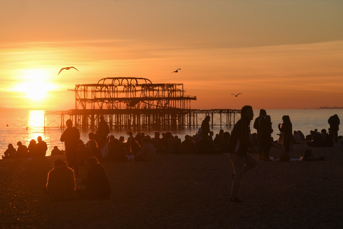 People enjoy the sunset on the beach by the derelict West Pier on February 25th, 2019, in Brighton, England.