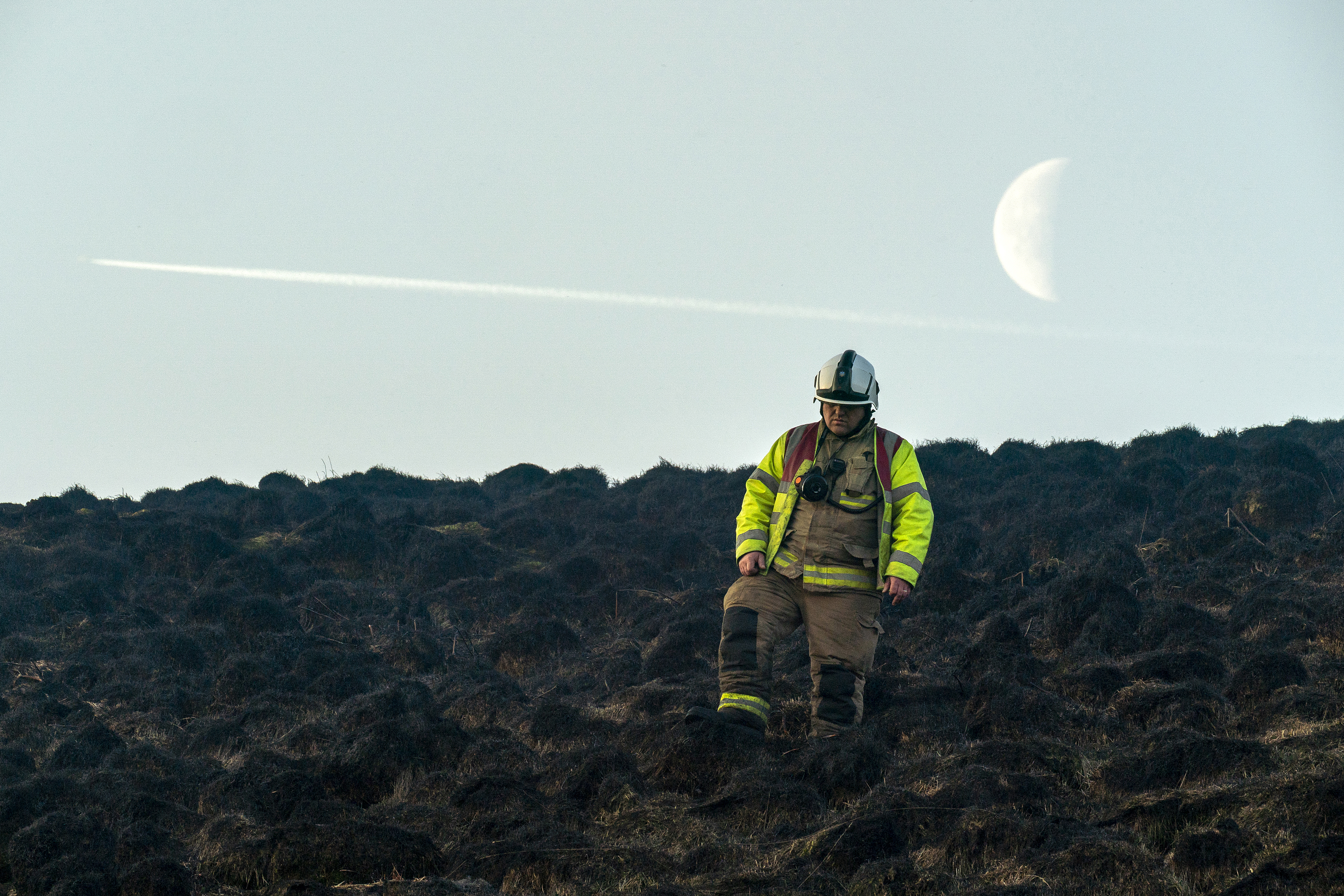 A firefighter makes their way across the charred moorland after extinguishing the heather and grass fire burning on Saddleworth Moor on February 27th, 2019, near Marsden, England.