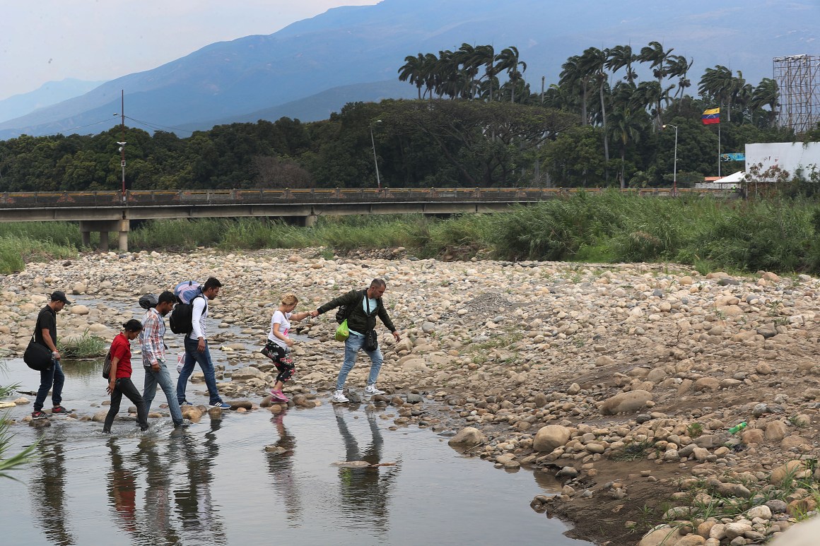 People cross through the low waters of the Táchira River near the Simón Bolívar international bridge, which connects Cúcuta, Colombia, with the Venezuelan town of San Antonio del Táchira, after the closure of the border bridge on February 27th, 2019, in Cúcuta, Colombia. Many people are making the trek through the river from Venezuela to get supplies or to escape the conditions in their country.