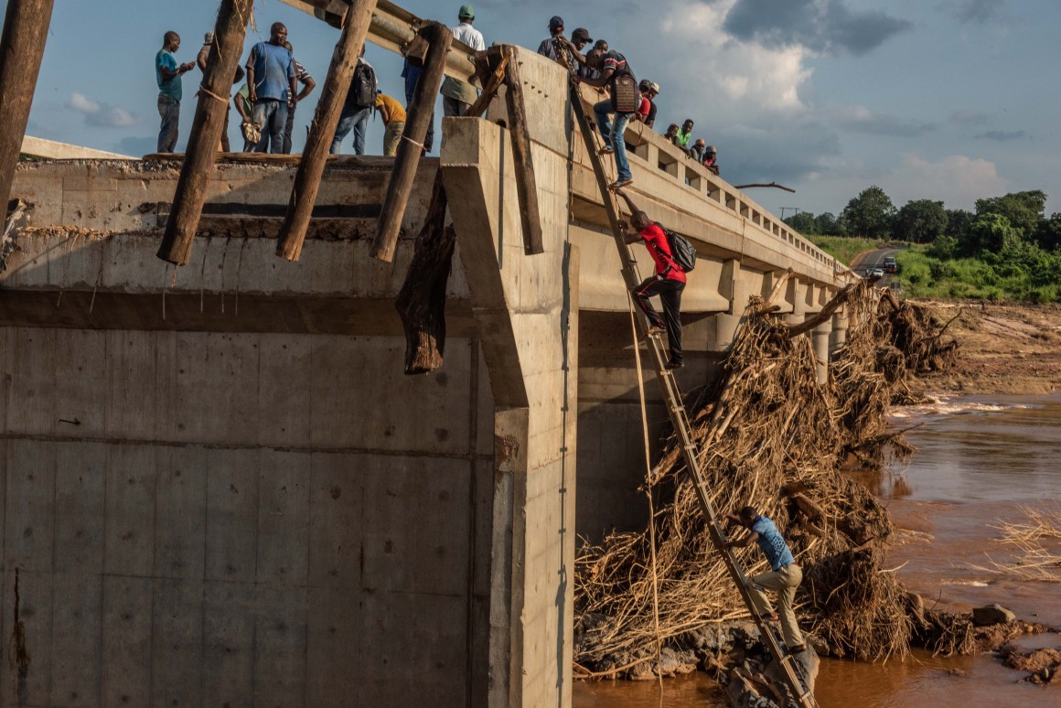 People scale a broken bridge, damaged during Cyclone Idai, to cross the Lucite River on March 26th, 2019, outside of Magaro, Mozambique. The storm caused the river to overflow and flood nearby villages. At least 156 bodies have been found in the surrounding area.