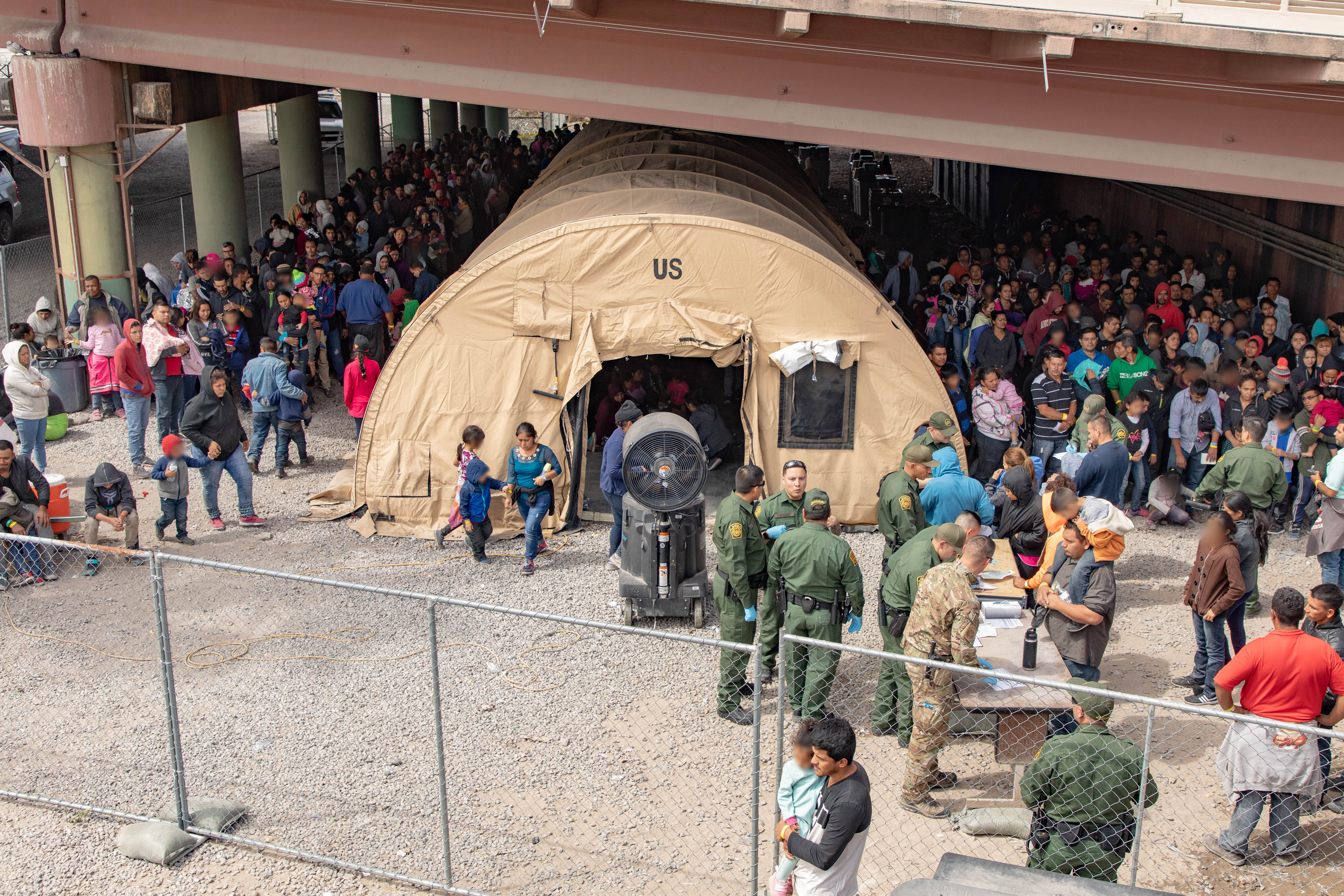 U.S. Border Patrol agents provide food, water, and medical screenings to scores of migrants and asylum seekers held underneath the international pedestrian bridge between the United States and Mexico on March 22nd in El Paso, Texas.