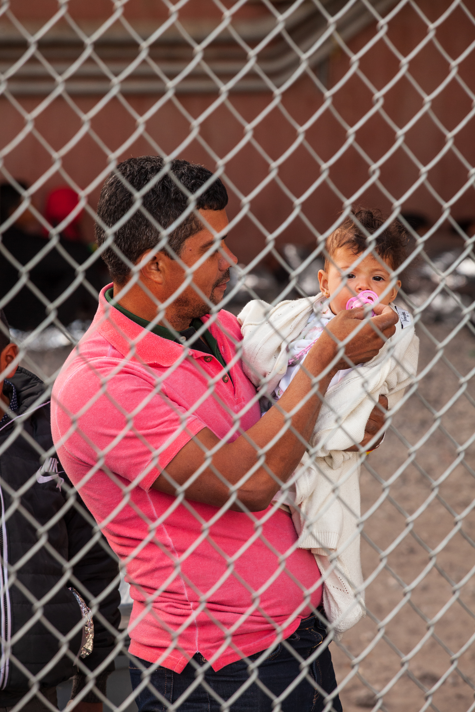 A man holds a child as both wait along with hundreds of other people in the temporary enclosure on March 28th.