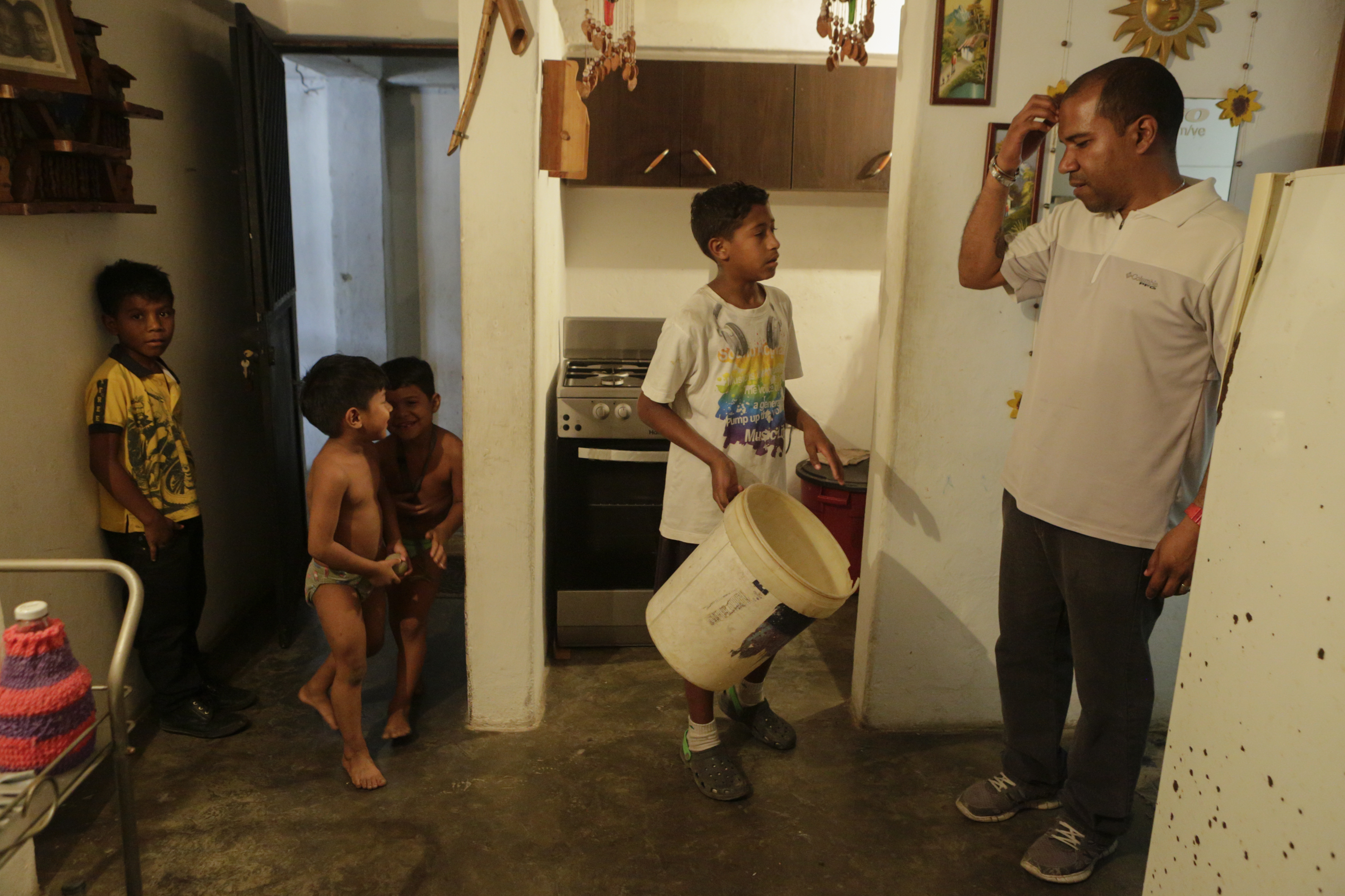 A man talks with children at his home, at the slum of Petare, on April 4th, 2019, in Caracas, Venezuela.