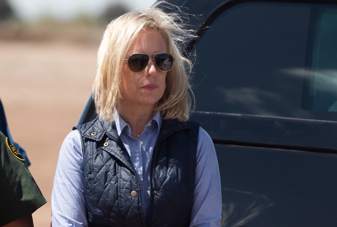 In this photo taken on April 5th, 2019, Secretary of Homeland Security Kirstjen Nielsen waits for President Donald Trump as he arrives to tour the border wall between the United States and Mexico in Calexico, California.