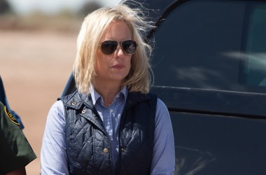 In this photo taken on April 5th, 2019, Secretary of Homeland Security Kirstjen Nielsen waits for President Donald Trump as he arrives to tour the border wall between the United States and Mexico in Calexico, California.