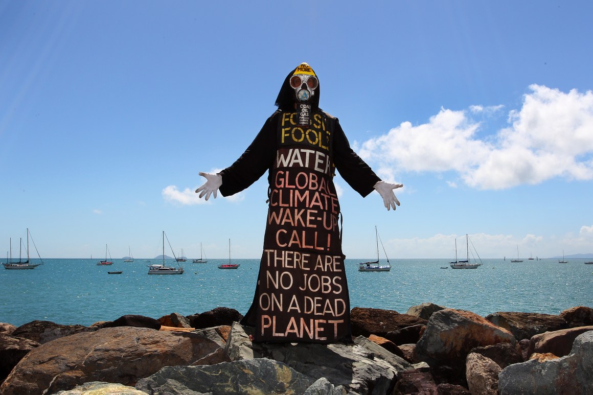 Benny Zable, a performance artist for peace and environment, stands in costume at the edge of Airlie Bay during an anti-Adani Carmichael coal mine rally on April 26th, 2019, in Airlie Beach, Australia.