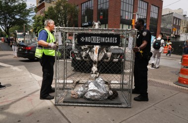 Police take away a pop-up art installation depicting a small child curled up underneath a foil survival blanket in a chain-link cage that stands along a Brooklyn street on June 12th, 2019, in New York City. Representing migrant children in Border Patrol custody, the cages were placed in front of the offices of various news organizations and other highly trafficked areas in Brooklyn and Manhattan.