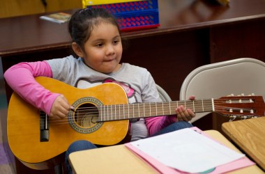 A young girl plays the guitar during guitar class at the Mariachi Academy in Harlem, New York.