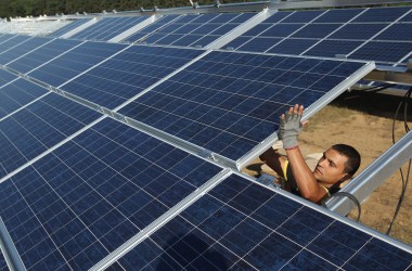 A worker installs solar panels containing photovoltaic cells.