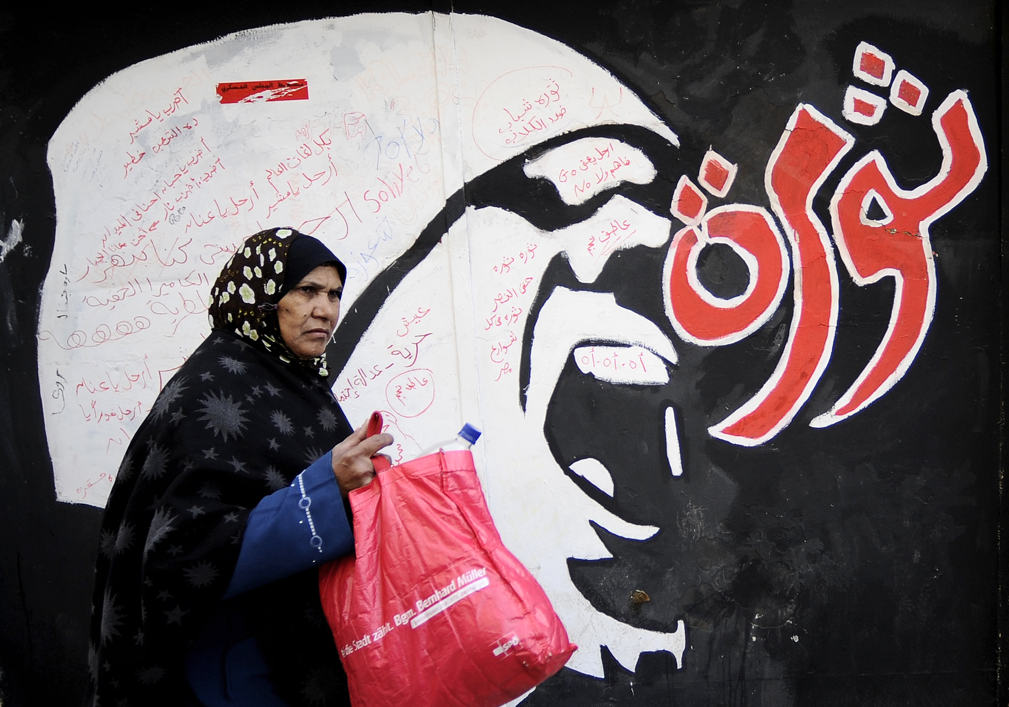 An Egyptian woman walks past graffiti near Tahrir Square in Cairo, Egypt, on December 21st, 2011.