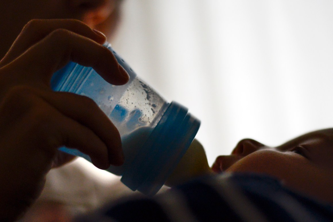 A mother feeds a baby with a bottle.