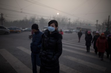 A woman wearing a mask crosses a road during severe pollution in Beijing on January 12th, 2013.