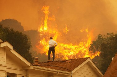 A man on a rooftop looks at approaching flames as the Springs fire continues to grow on May 3rd, 2013, near Camarillo, California.