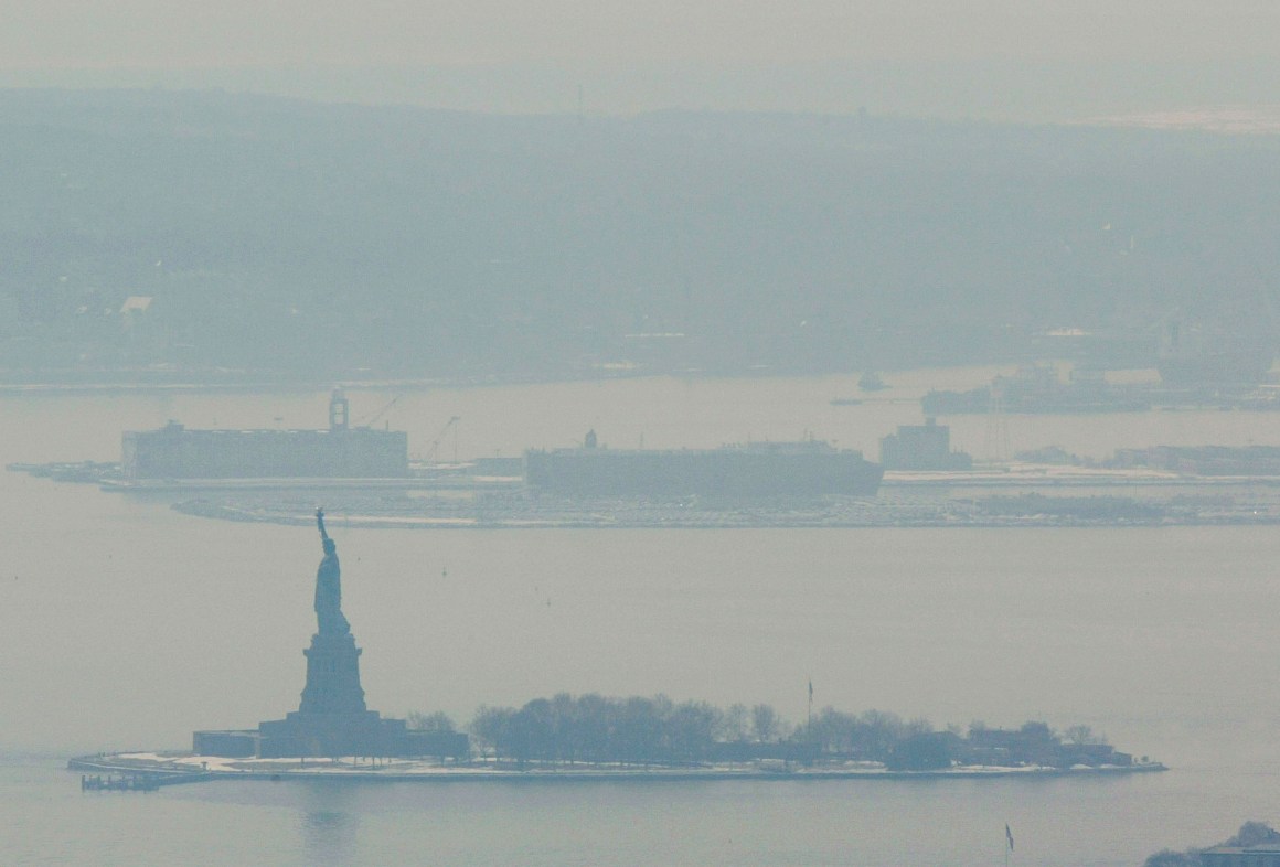 A hazy smoke hangs over Liberty Island after a storage facility explosion in nearby Staten Island February 21st, 2003 in New York.