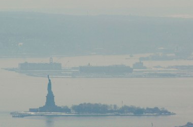 A hazy smoke hangs over Liberty Island after a storage facility explosion in nearby Staten Island February 21st, 2003 in New York.