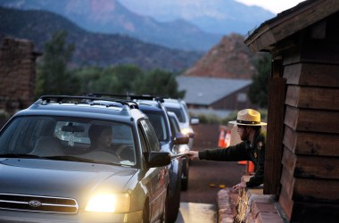 A park ranger Lee Wilson (R) passes out park information to visitors at the entrance to Zion National Park in Springdale, Utah.