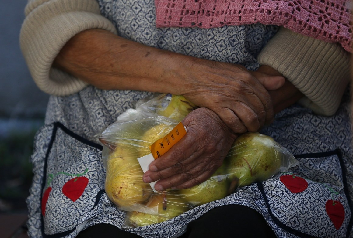 A woman holds a bag of pears as she waits in line to receive free food at the Richmond Emergency Food Bank on November 1st, 2013, in Richmond, California.