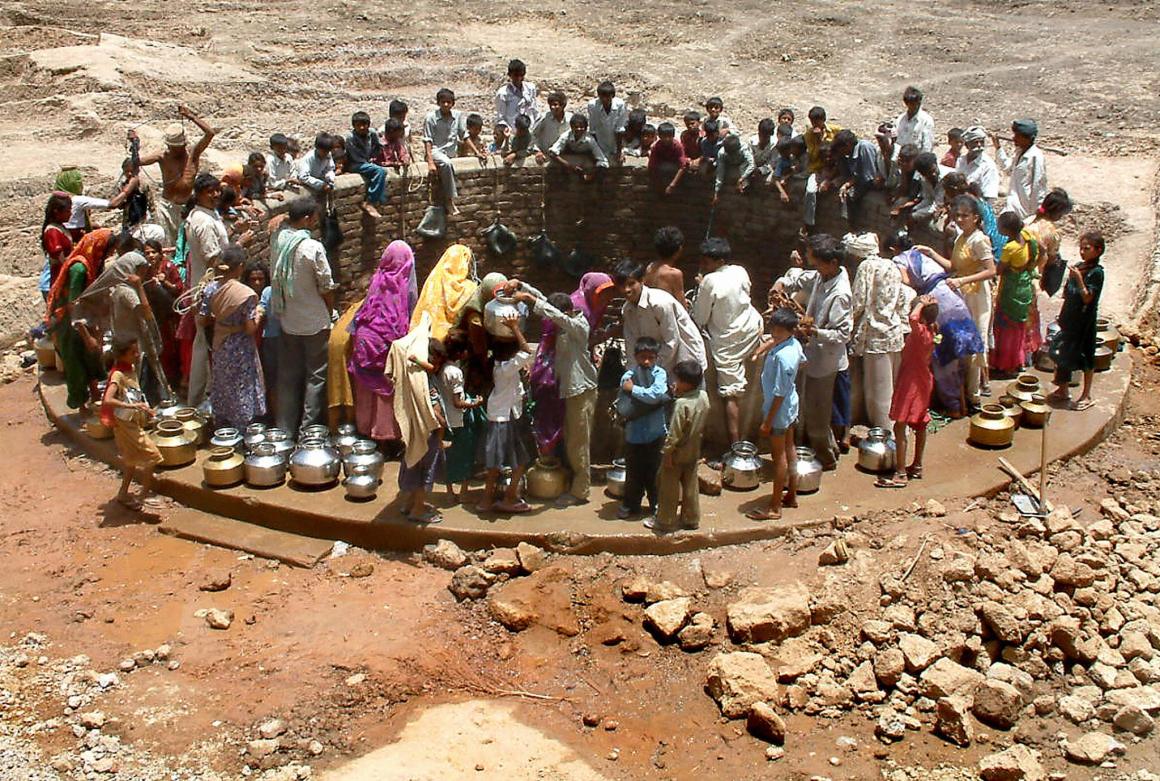 Indian villagers gather around a well to fill their pots with water at Natwargadh village.