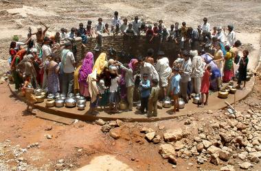 Indian villagers gather around a well to fill their pots with water at Natwargadh village.