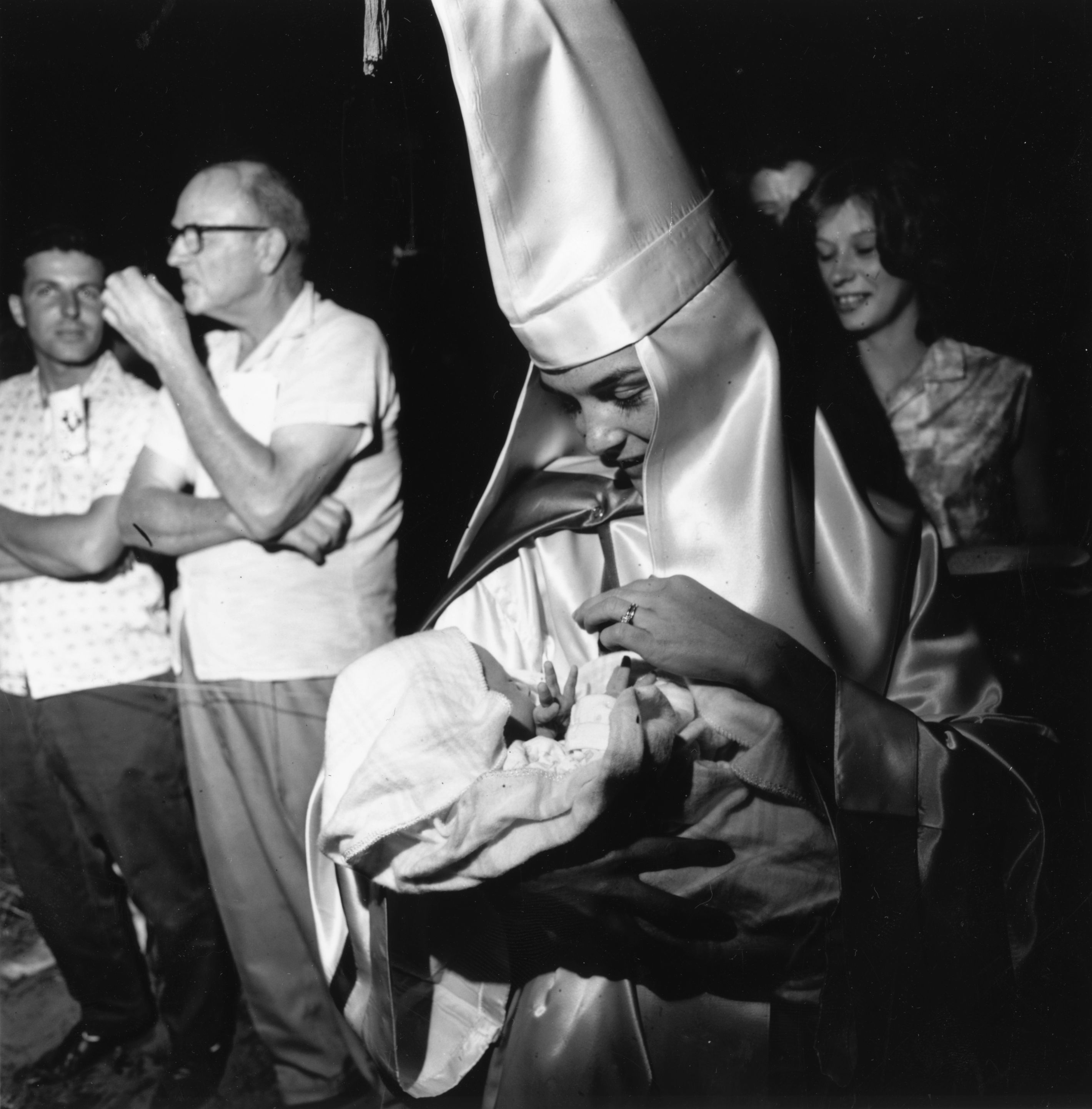 A woman wearing the robes and hood of the Ku Klux Klan holds her baby at a Klan meeting in Beaufort, South Carolina, on May 24th, 1965.