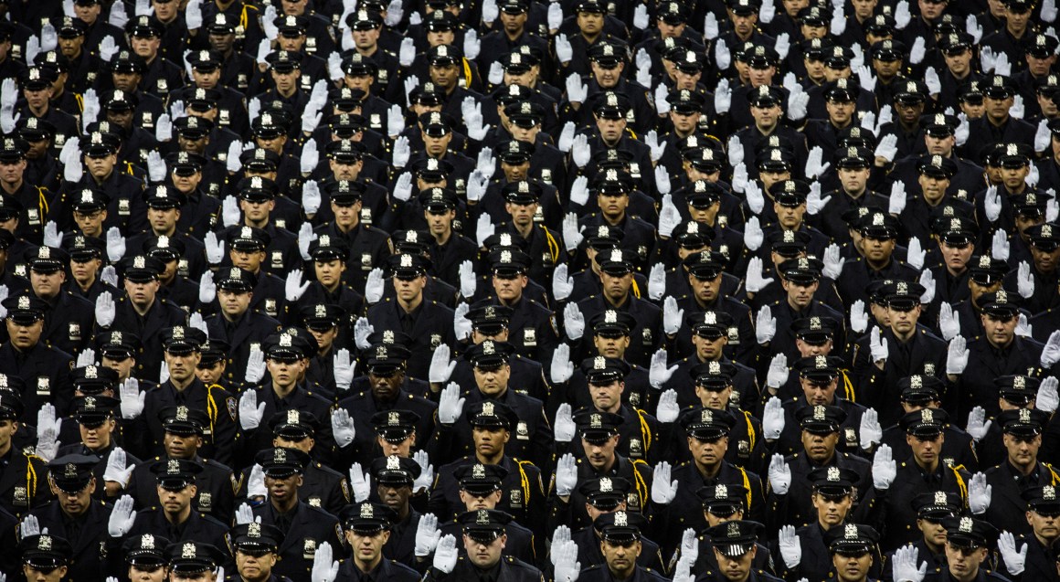 The 2014 class of the New York Police Department raise their hands while taking an oath on June 30th, 2014, at Madison Square Garden in New York City.