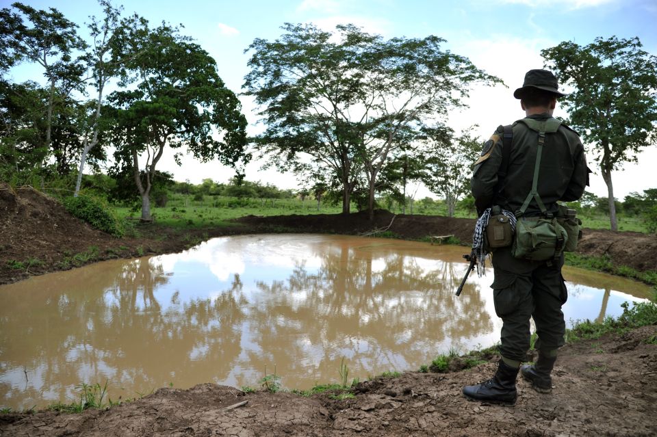 A police officer stands guard during a government land restitution process. Farmers were displaced under pressure and threats from former paramilitary commander Rodrigo Tovar Pupo.