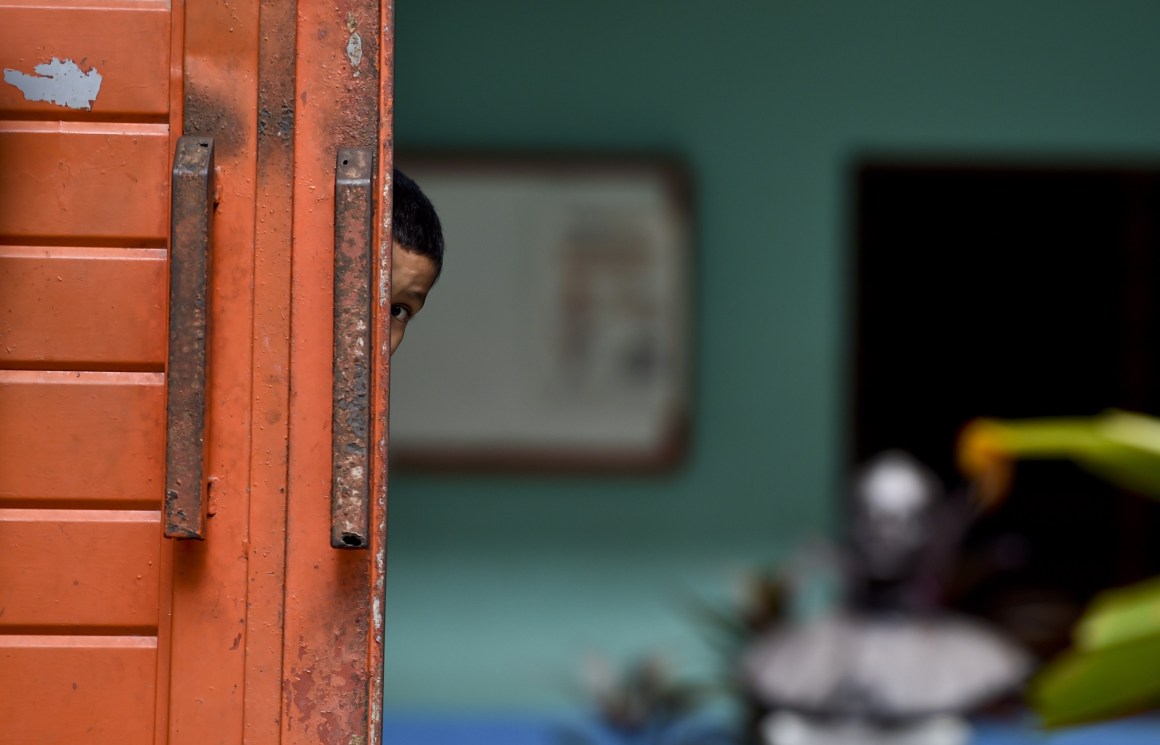 A migrant child watches behind the main door of a shelter in Tapachula, Mexico, where he's taken a rest during his attempt to reach the border between Mexico and the United States.