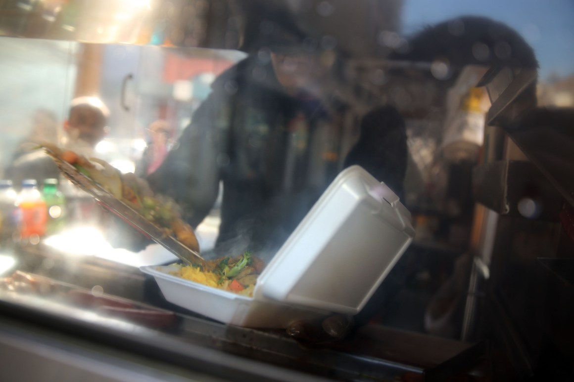 A food cart worker fills a styrofoam take-out container with food for a customer on December 19th, 2013, in New York City.