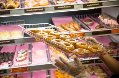 A Dunkin' employee places a fresh tray of doughnuts on the shelf in New York City.