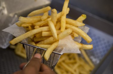 A cook prepares french fries from a fryer in the kitchen at Bolt Burgers in Washington, D.C.