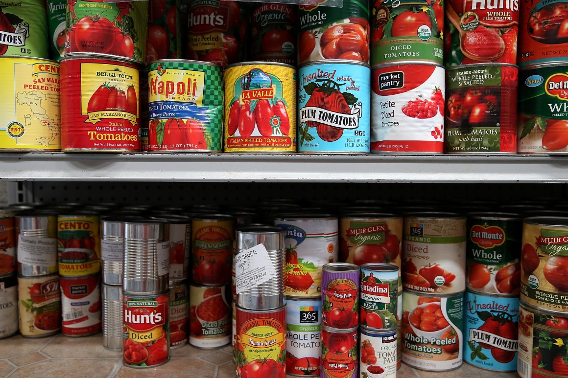 Canned tomatoes line the shelves of a food pantry.