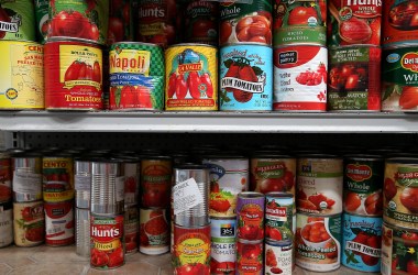 Canned tomatoes line the shelves of a food pantry.