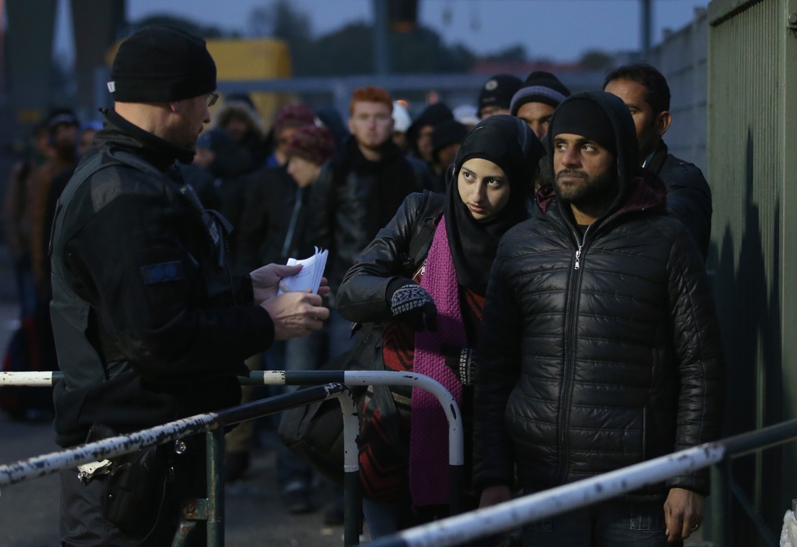 A German police officer directs migrants arriving from Austria at the border on October 17th, 2015, in Ering, Germany.