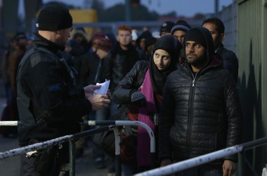 A German police officer directs migrants arriving from Austria at the border on October 17th, 2015, in Ering, Germany.