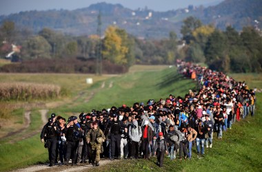 Migrants are escorted through fields by police and the army as they are walked from the village of Rigonce to Brezice refugee camp on October 24th, 2015, in Rigonce, Slovenia.