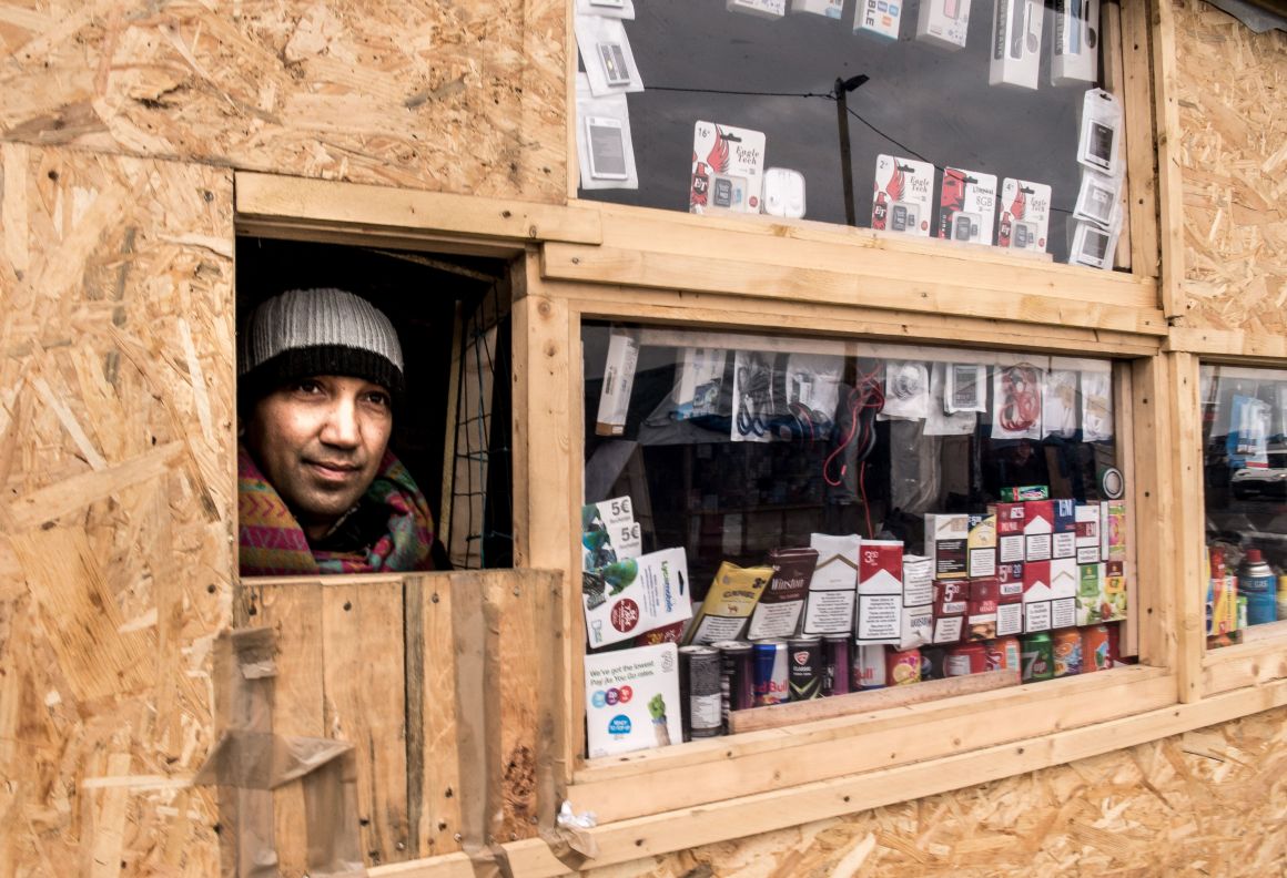 A Pakistani migrant looks out of his shop set-up at "the Jungle" in the French port city of Calais.