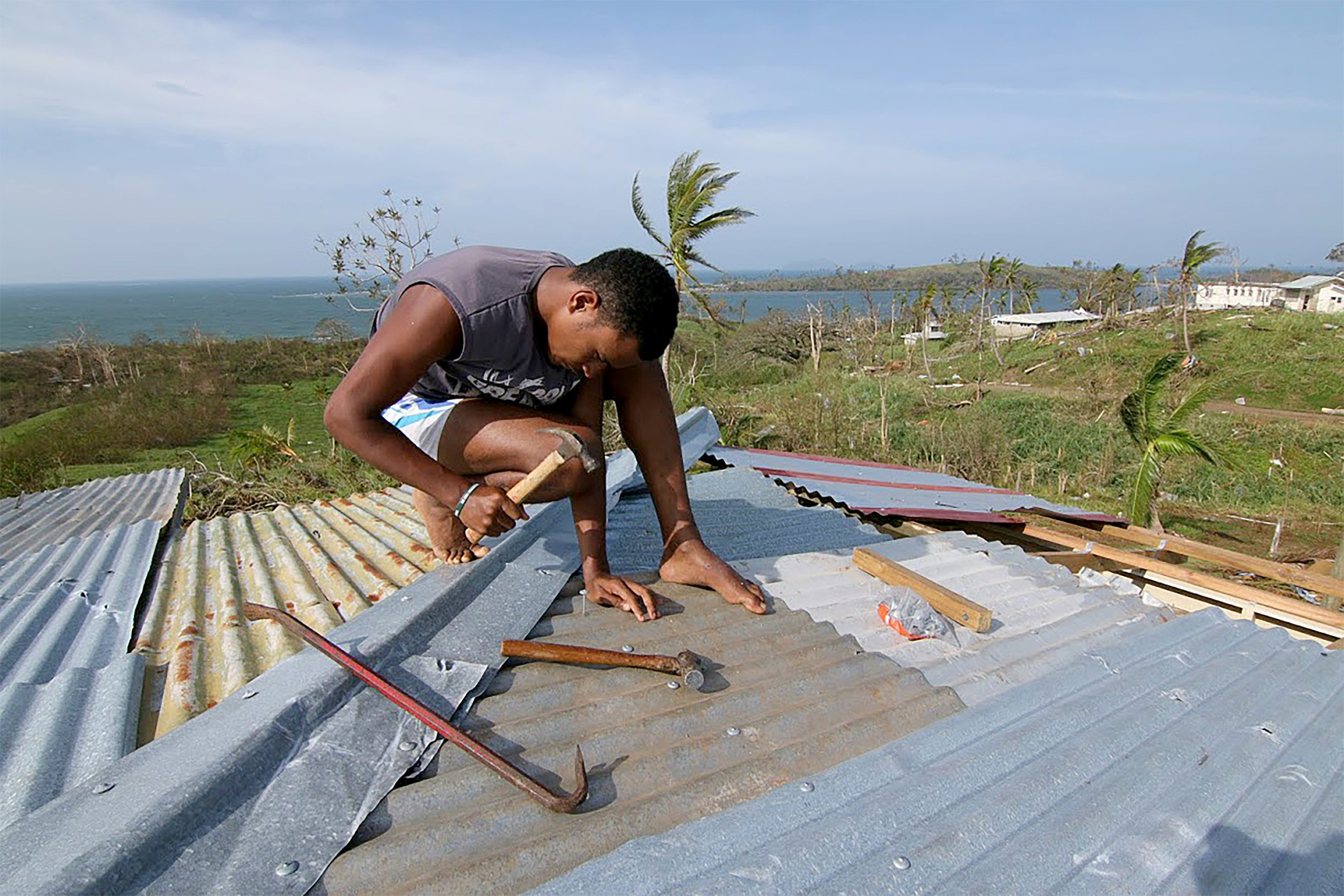 A young man repairs the roof of his house in Tailevu after Cyclone Winston swept through Fiji in 2016.