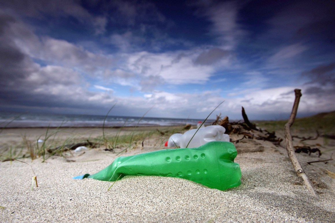 Plastic bottles and general rubbish washed up by the sea litter a beach.