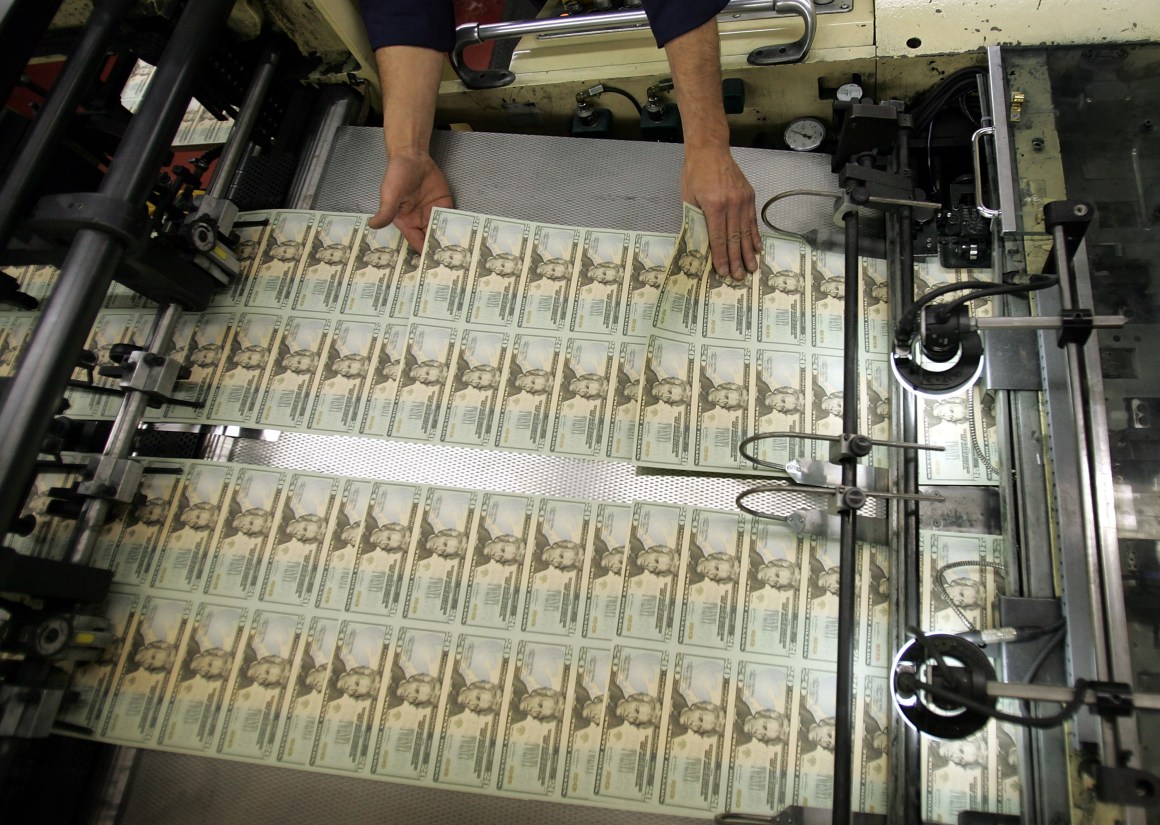 A worker looks for defective bills in the sheets of newly printed $20 bills at the Department of the Treasury in Washington, D.C.