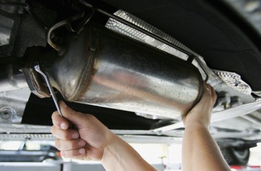 A car mechanic fits a particle filter to a diesel-engined car.