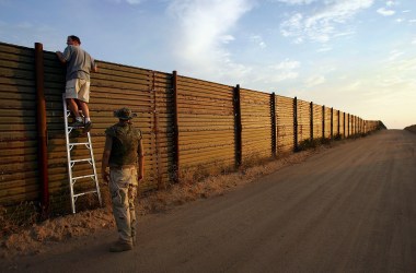 Volunteers look over the U.S.–Mexico border fence.