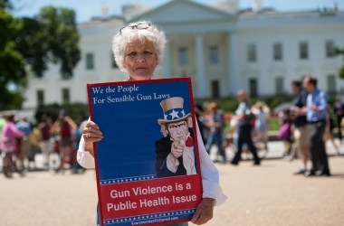 A woman walks with a sign to protest gun violence and call for sensible gun laws outside the White House in June of 2016. One advocacy group, Cure Violence, approaches violence as a public-health issue, and has seen success reducing gun violence.