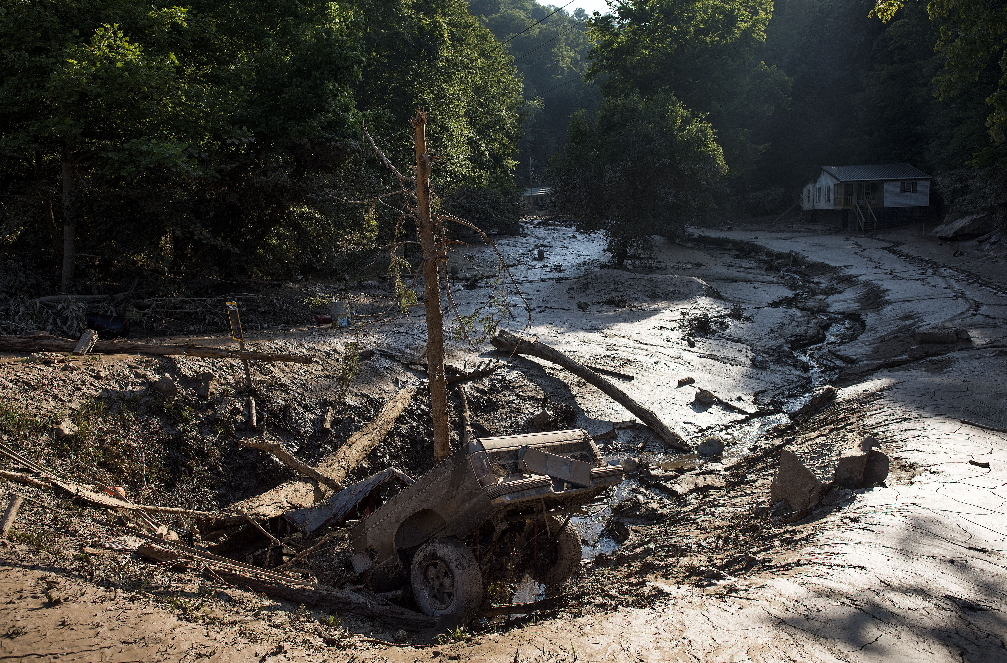 A truck lies in a hole among the mud after it was washed out of the driveway from the flooding on June 25th, 2016, in Clendenin, West Virginia.